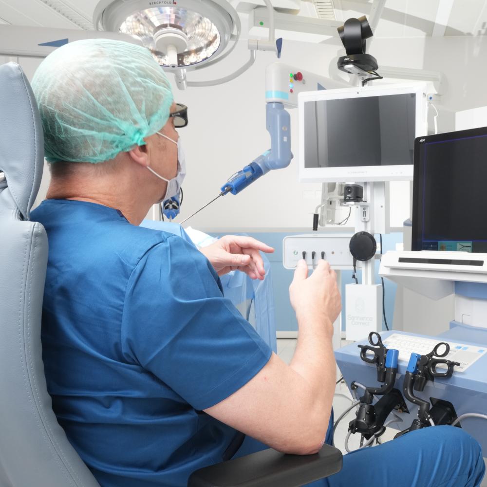 A surgeon looking at a monitor with his hands extended in front of him